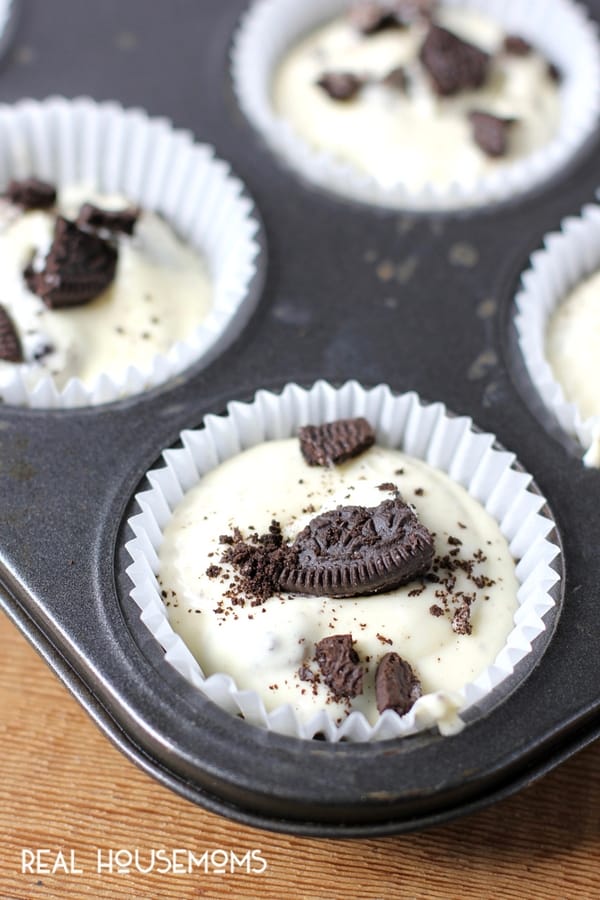 Unbaked Mini Oreo Cheesecakes in muffin tin trays, topped with chopped up Oreo cookies