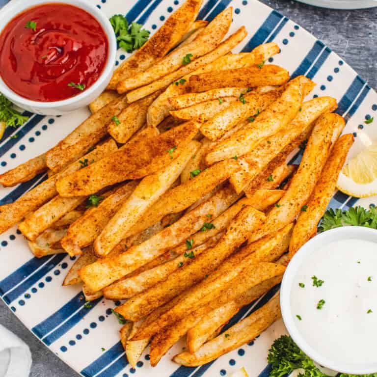 square image of oven baked crabfries on a platter with a bowls of ketchup and ranch for dipping