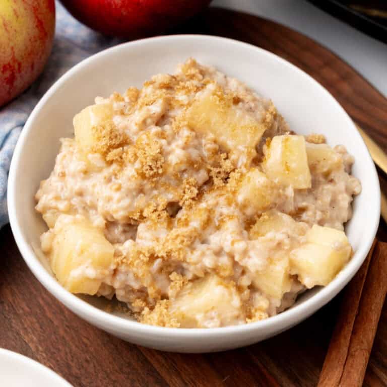square image of a bowl of overnight crock pot apple pie oatmeal topped with brown sugar