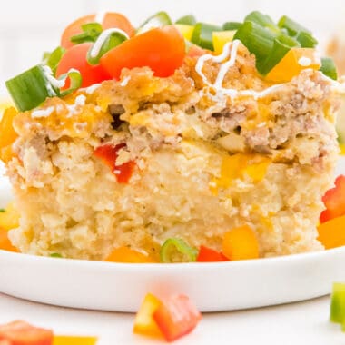 square image of overnight crock pot breakfast casserole on a plate topped with tomatoes and green onion