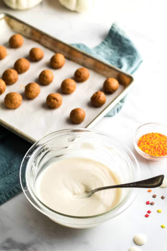 vanilla candy coating melted in a bowl next to pumpkin pie filling balls