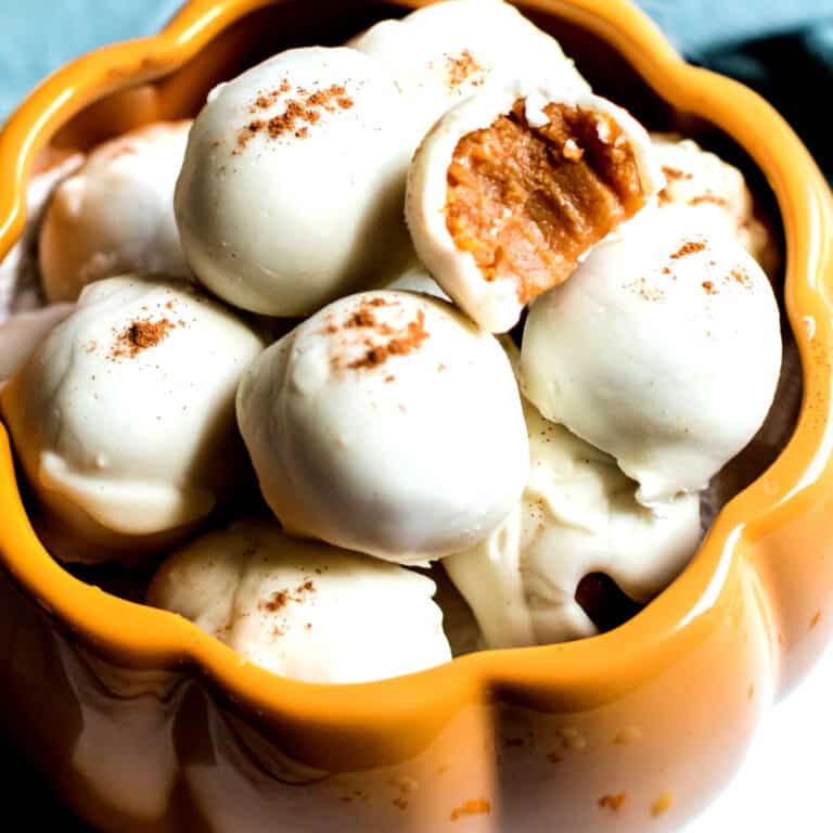 square image of pumpkin pie truffles in a bowl with one bite taken out to show filling