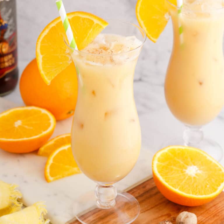 square image of a painkiller cocktail garnished with an orange slice and a straw