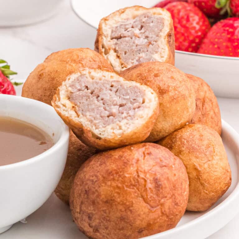 square image of pancake sausage bites on a plate with one cut in half to show the filling