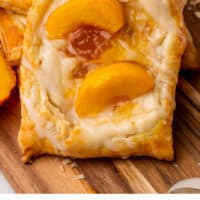 peach cream cheese danish on a wooden tray with more danishes with recipe name at the bottom