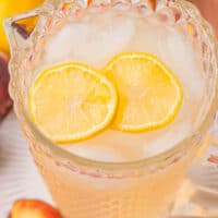 square image looking down into a pitchers of peach lemonade with lemon slices floating on top
