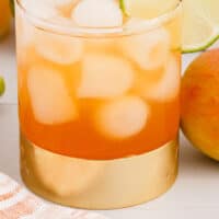 peach mango rum splash in a rocks glass with a lime slices for garnish with recipe name at the bottom