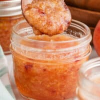 spoonful of peach pineapple freezer jam over the jar with recipe name at the bototm