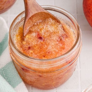 square image of a spoon of peach pineapple freezer jam being lifted from the jar