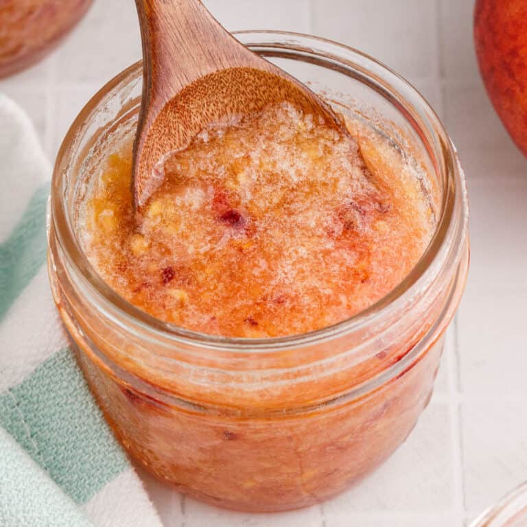 square image of a spoon of peach pineapple freezer jam being lifted from the jar