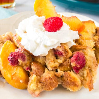 square image of peach raspberry slow cooker french toast with whipped cream