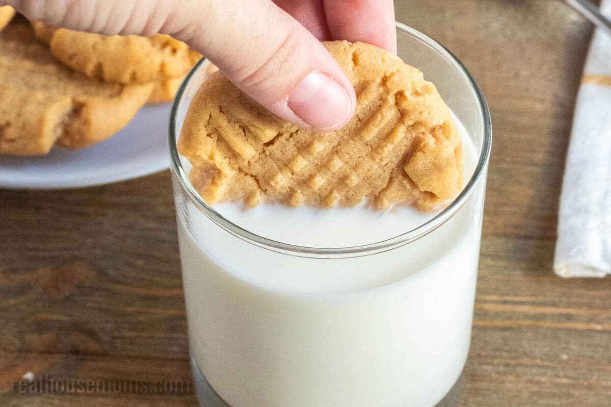 a peanut butter cookie being dipped into a glass of milk