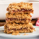 square image of three peanut butter and jelly oatmeal bars stacked up on a palte