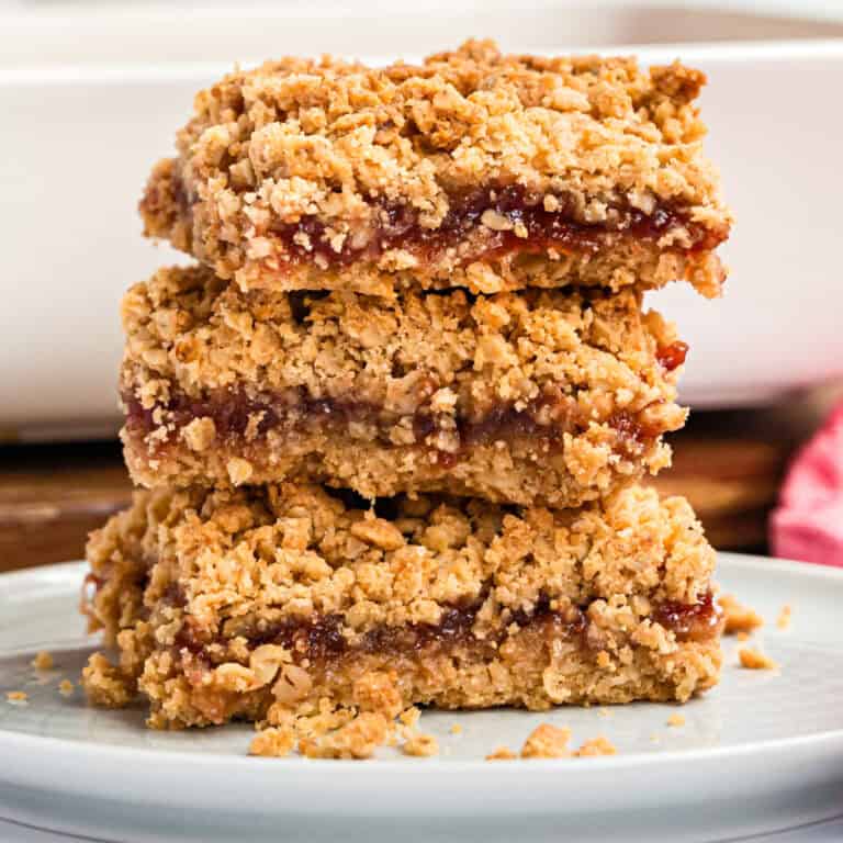 square image of three peanut butter and jelly oatmeal bars stacked up on a palte