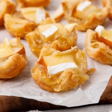 square image of pear caramelized onion and brie bites on a serving tray with parchment paper