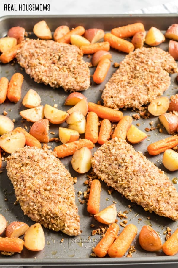 pecan chicken with potatoes and carrots on a baking sheet