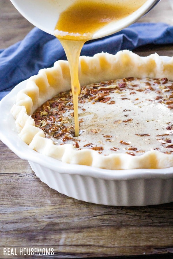 pecan pie filling being poured into a pie crust