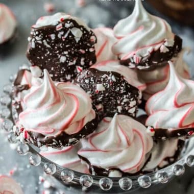 These sweet Peppermint Bark Meringues are made with just a handful of ingredients!  They’re adorably festive with candy cane stripes, dipped in dark chocolate, and sprinkled with crushed candy cane pieces!