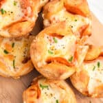 square image of pepperoni pizza puffs piled up on a wooden board