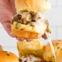 picture of of philly cheesesteak sliders being shown how cheesy it is. with the title of the post on the top of the picture in pink and black lettering