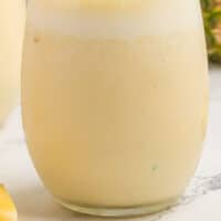 pineapple banana smoothie in a stemless wineglass with recipe name at the bottom