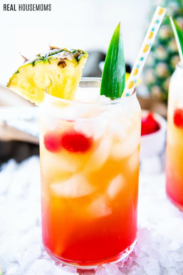 close up of rum punch garnished with pineapple and cherries
