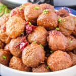 square image of pinot noir & cranberry meatballs piled up in a serving bowl with chopped chives for garnish