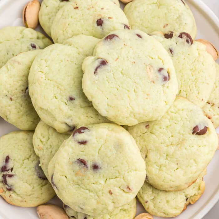 square image of pistachio chip cookies piled up on a plate