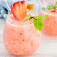 square image of frozen peach margarita in a stemless wine glass with fruit and mint garnish