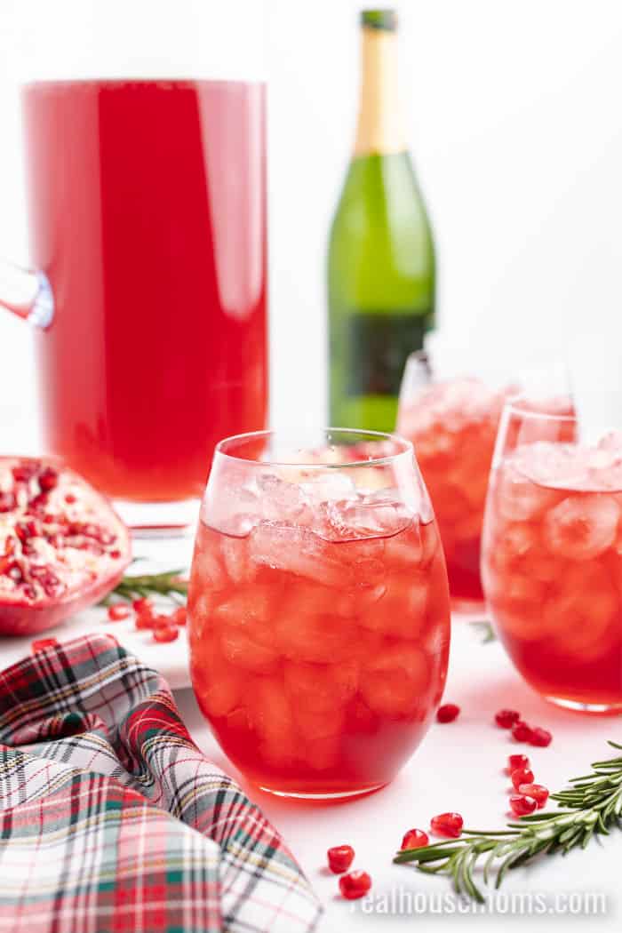 wine glass with pomegranate champagne cocktail over ice