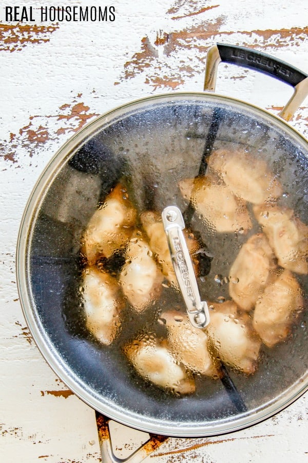 pot stickers in a skillet with the lid on