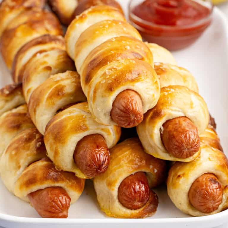 square image of pretzel wrapped hot dogs piled on a serving platter