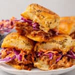 square image of three pulled pork sliders stacked up on a plate