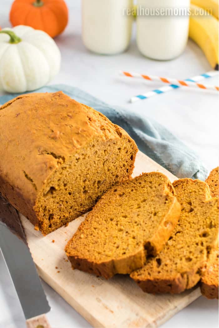 pumpkin banana bread loaf with half cut into slices on a cutting board