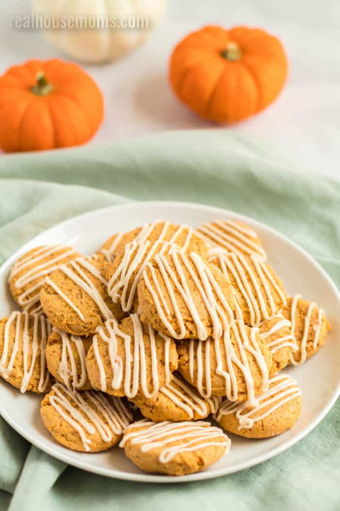 pumpkin cookies with maple frosting piled up on a plate