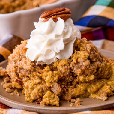 square image of pumpkin crisp topped with whipped cream and a pecan