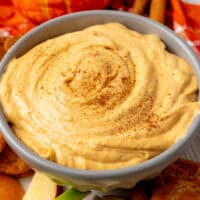 square image of pumpkin mousse dip topped with a sprinkle of pumpkin pie spice in a serving bowl