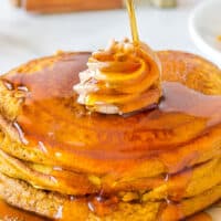 syrup being poured over pumpkin pancakes with recipe name at the bottom