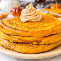 square image of pumpkin pancakes stacked with pumpkin spice butter on top