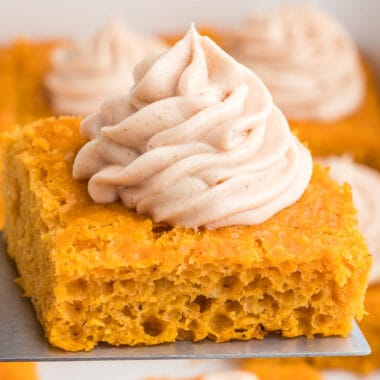 square image of pumpkin pie angel food cake with cinnamon cream cheese frosting on a spatula