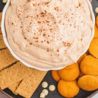 pumpkin pie cheesecake dip in a serving bowl on a tray with dippers with recipe name at the bottom