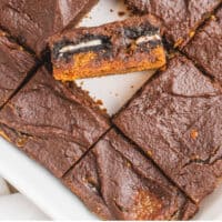 pumpkin slutty brownies in a baking dish, one turned on its side with recipe name at the bottom