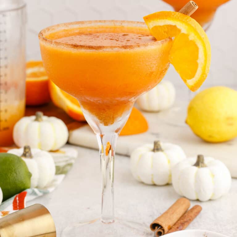 square image of a pumpkin spice margarita with orange and cinnamon stick garnish