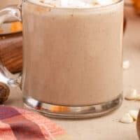 side view of glass mug of pumpkin white hot chocolate with recipe name at the bottom