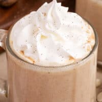 image of pumpkin white hot chocolate topped with whipped cream in a glass mug with thte title of the post is on top of the image in orange and black lettering