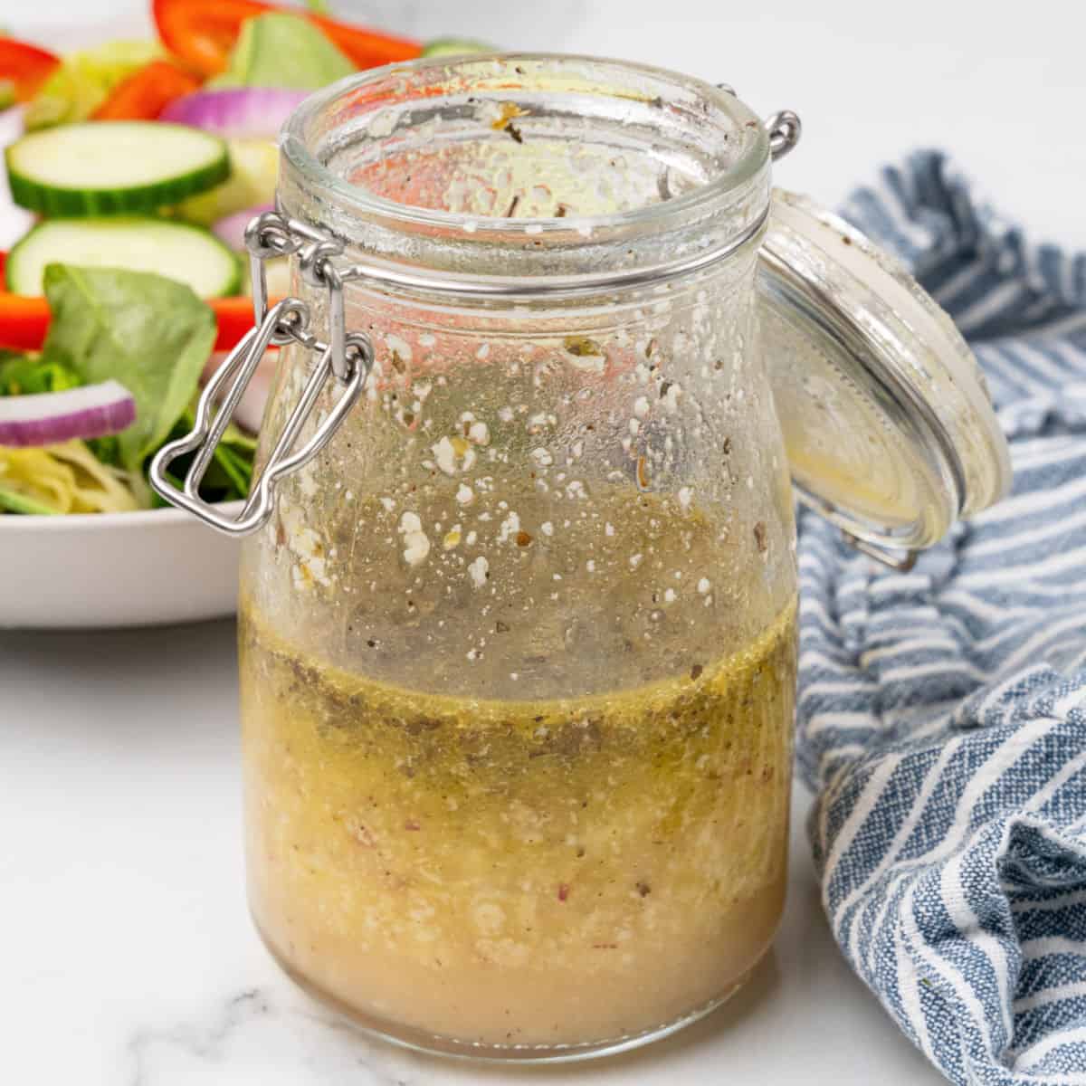 square image of italian dressing in a jar next to a salad