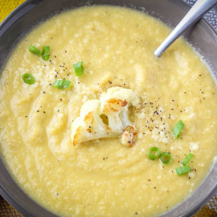 Pic of close up of Roasted Garlic Cauliflower Soup in a grey bowl with a spoon