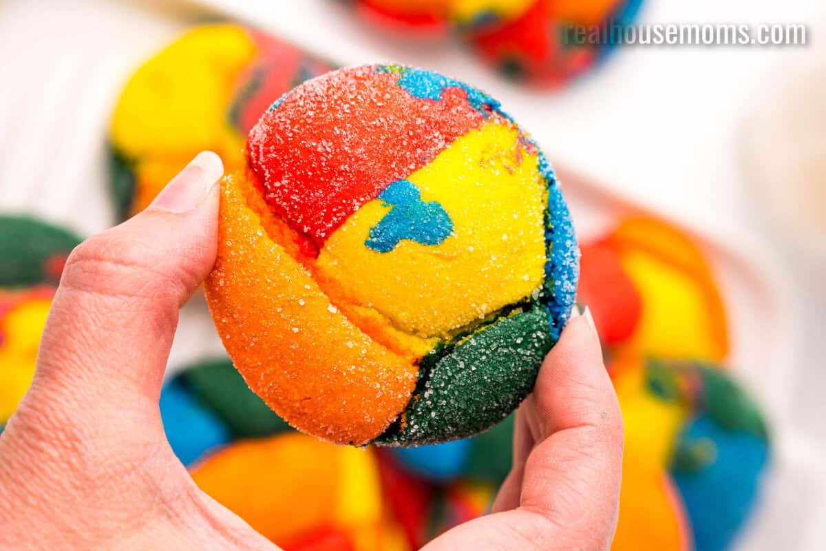 close up of a hand holding a rainbow cake mix cookie