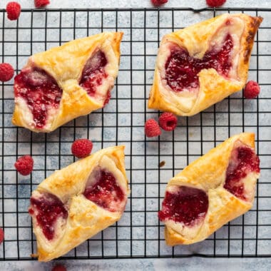 square image of raspberry cheese danishes on a wire rack with fresh raspberries