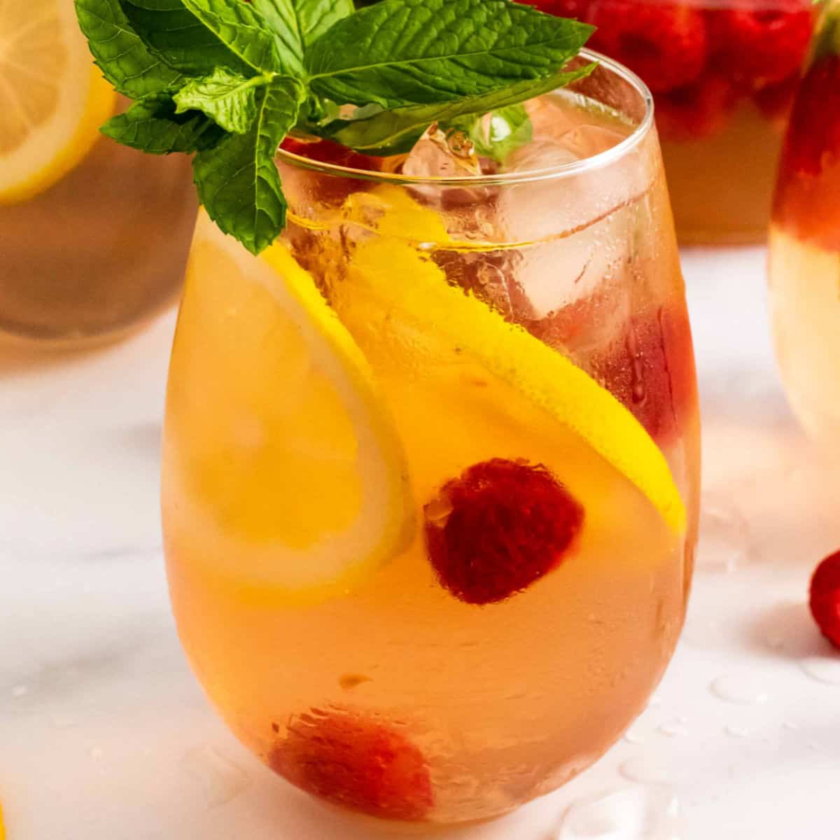 square image of Raspberry Lemonade Moscato Sangria in a stemless wine glass with fruit garnish